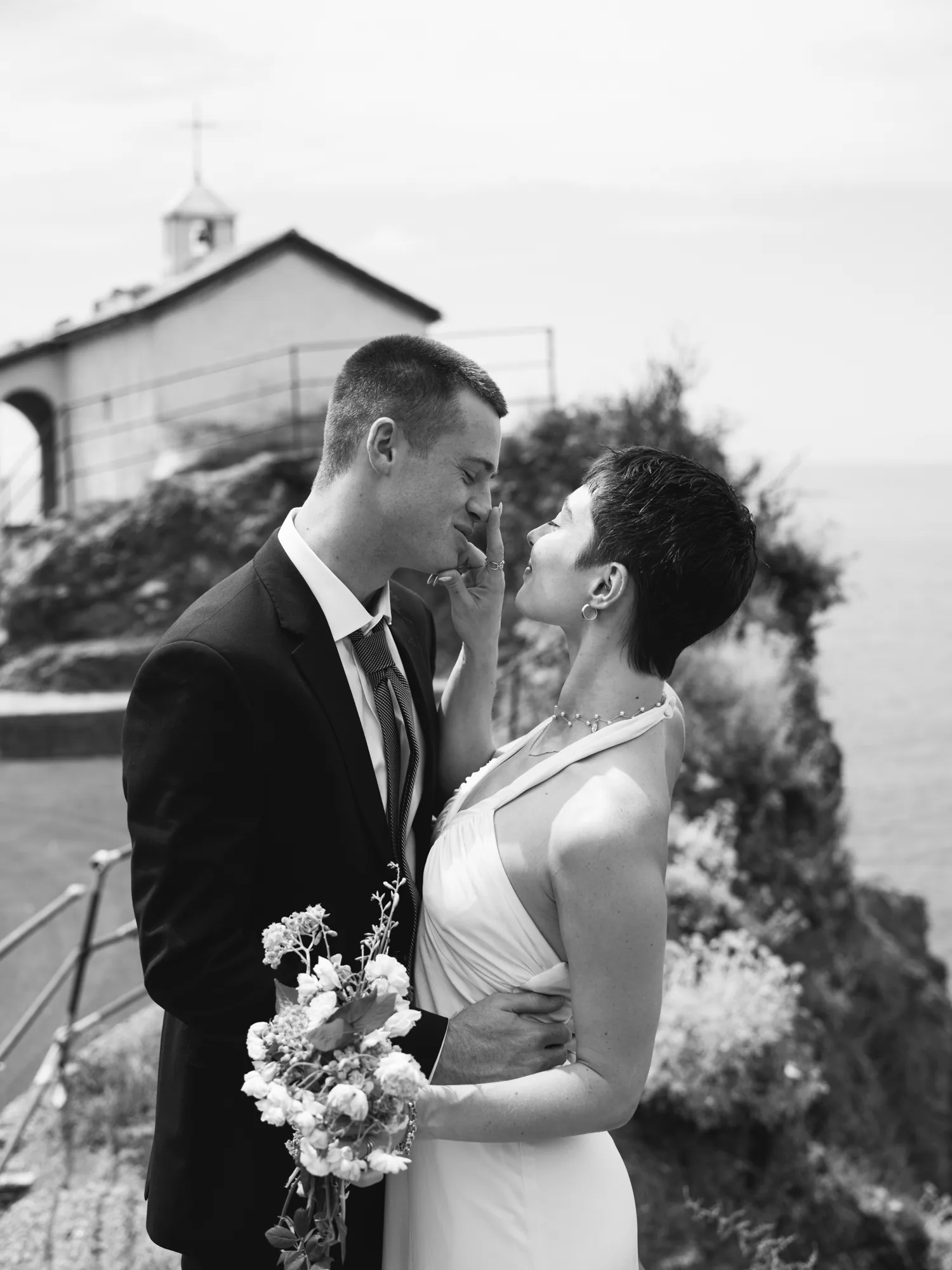 The photograph is in black and white, featuring a couple standing close together outdoors.