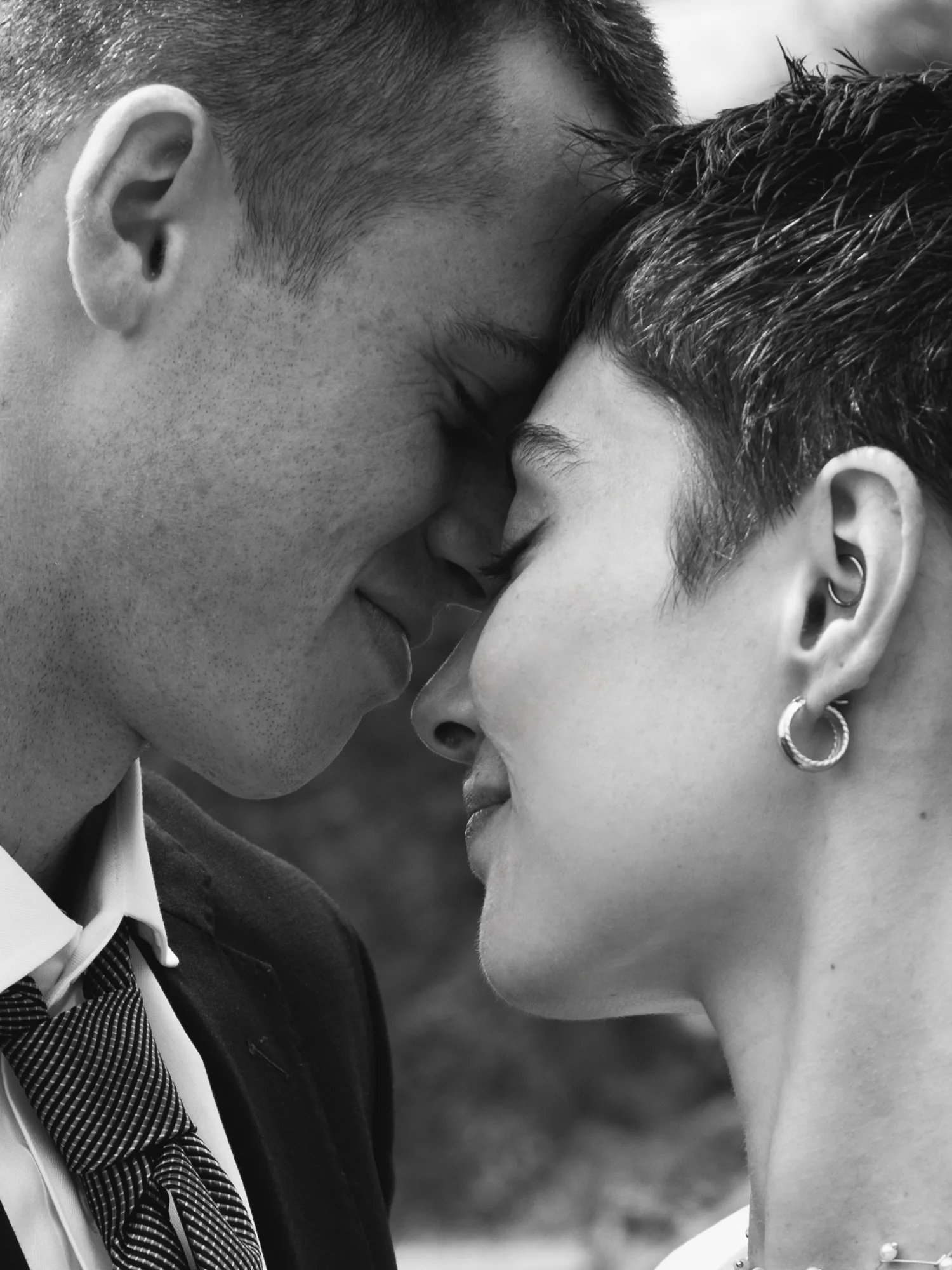 The photograph is in black and white, showing a close-up of a groom and a bride's faces.