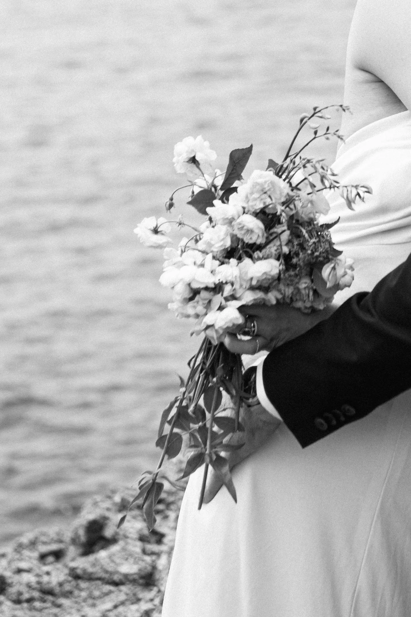 The photograph is in black and white, showing a close-up of a person's hand holding a bouquet of flowers.