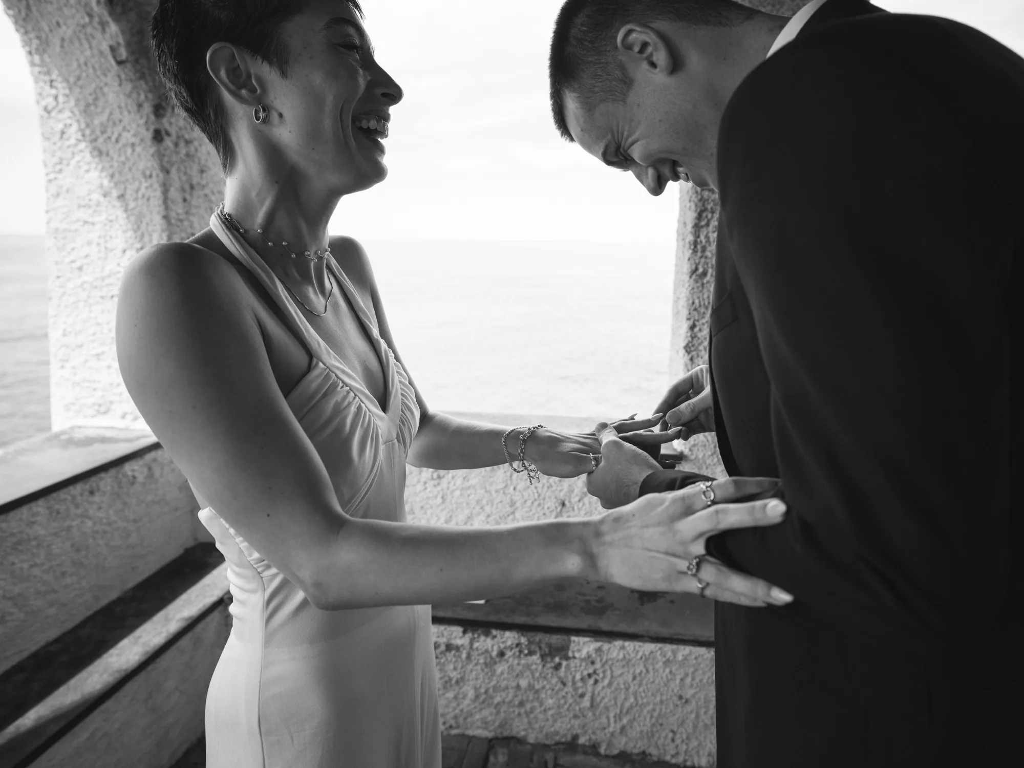 The bride and groom laughing while putting a wedding ring on brides hand