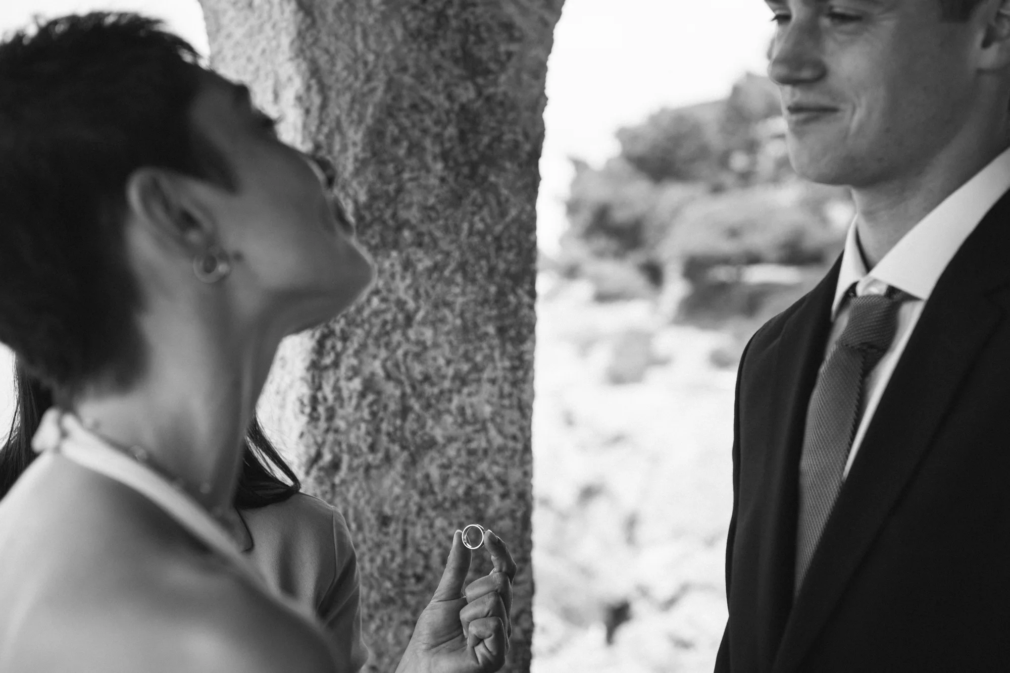 A bride is holding a ring, and the groom is looking at the ring.
