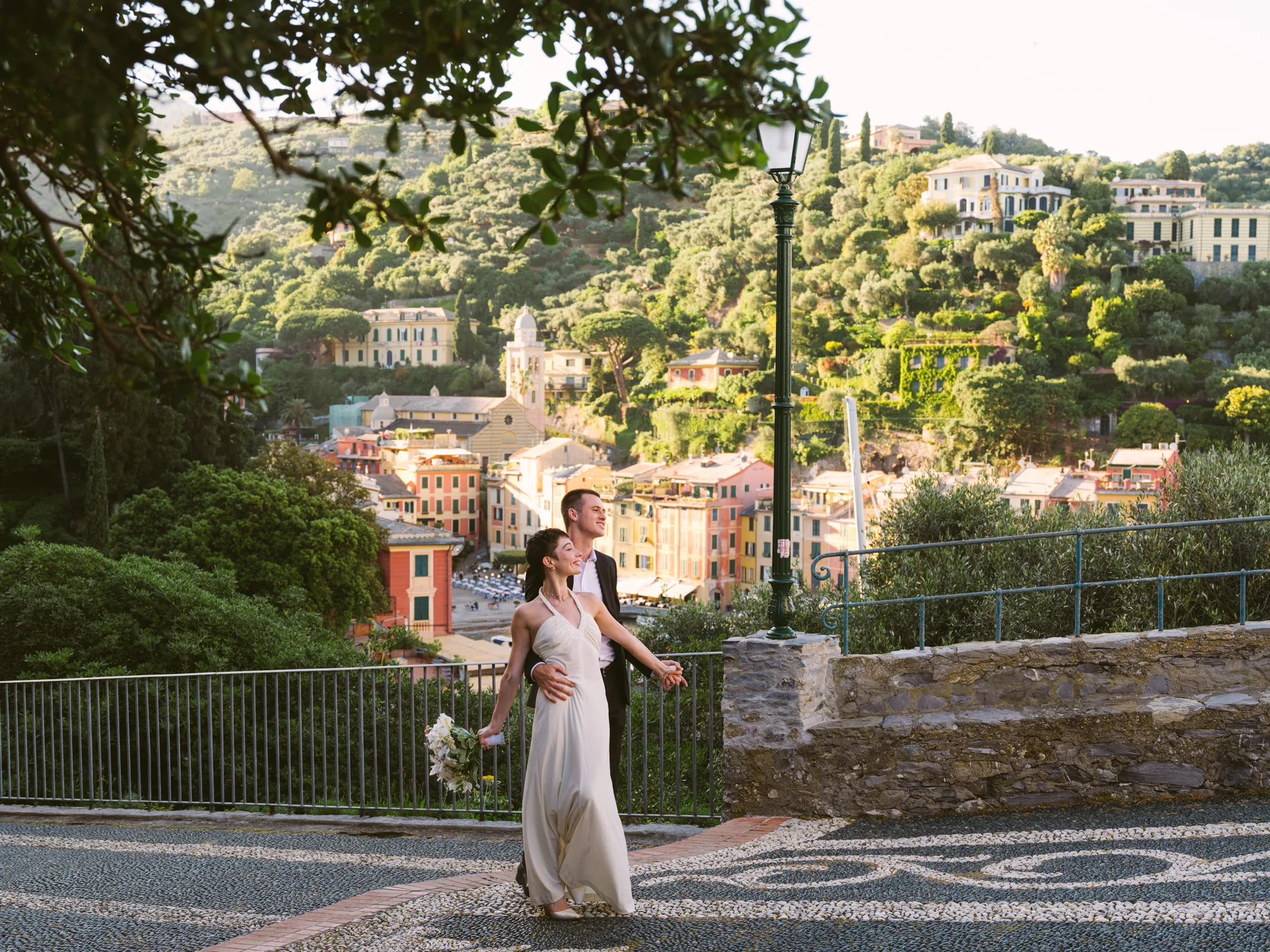 A bride in a white dress holds a bouquet of flowers as she walks hand-in-hand with a person.