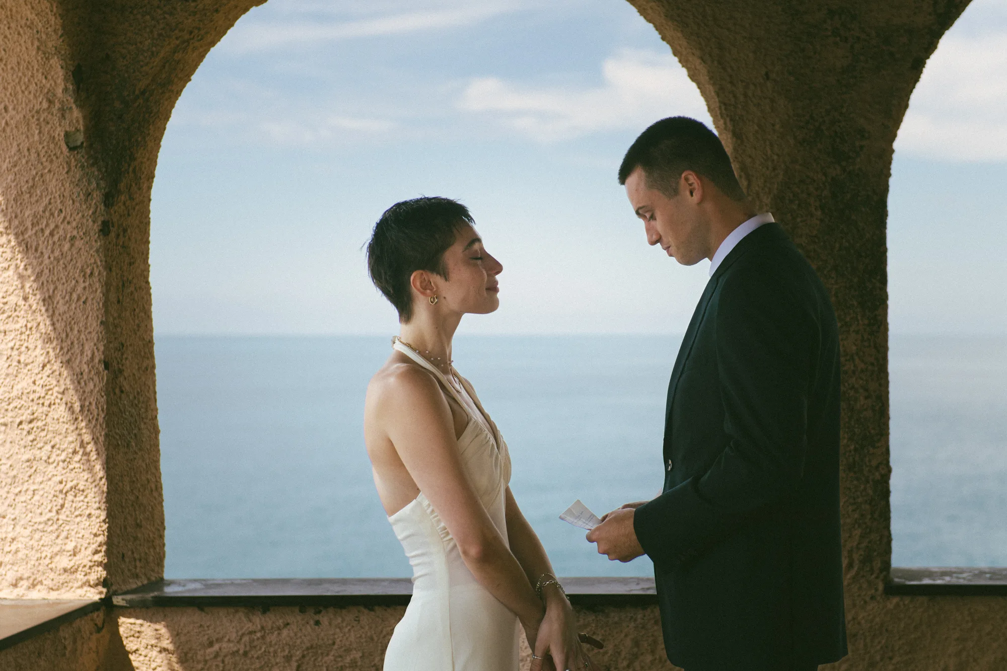 A couple stands under an archway, gazing into each other's eyes.