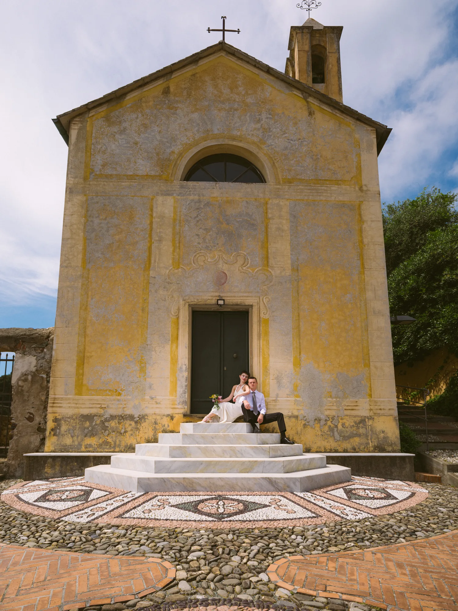 Ex Oratorio di Sant’Erasmo church with a couple sitting on steps in front of the church in Bonassola