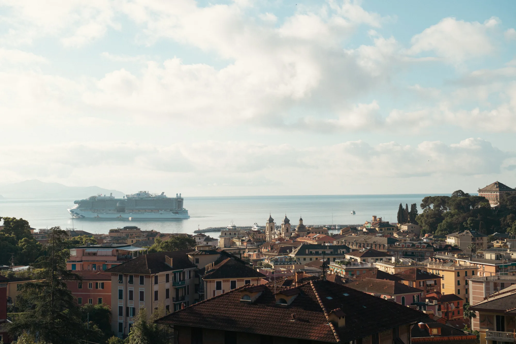 A large cruise ship is docked in the harbor, surrounded by a mix of modern and traditional buildings.