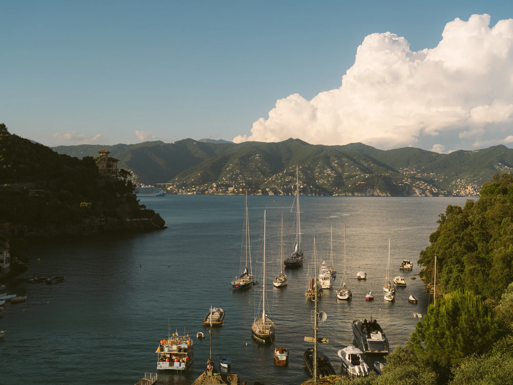 The photograph shows a serene harbor with several boats docked, including sailboats and motorboats, in calm waters.