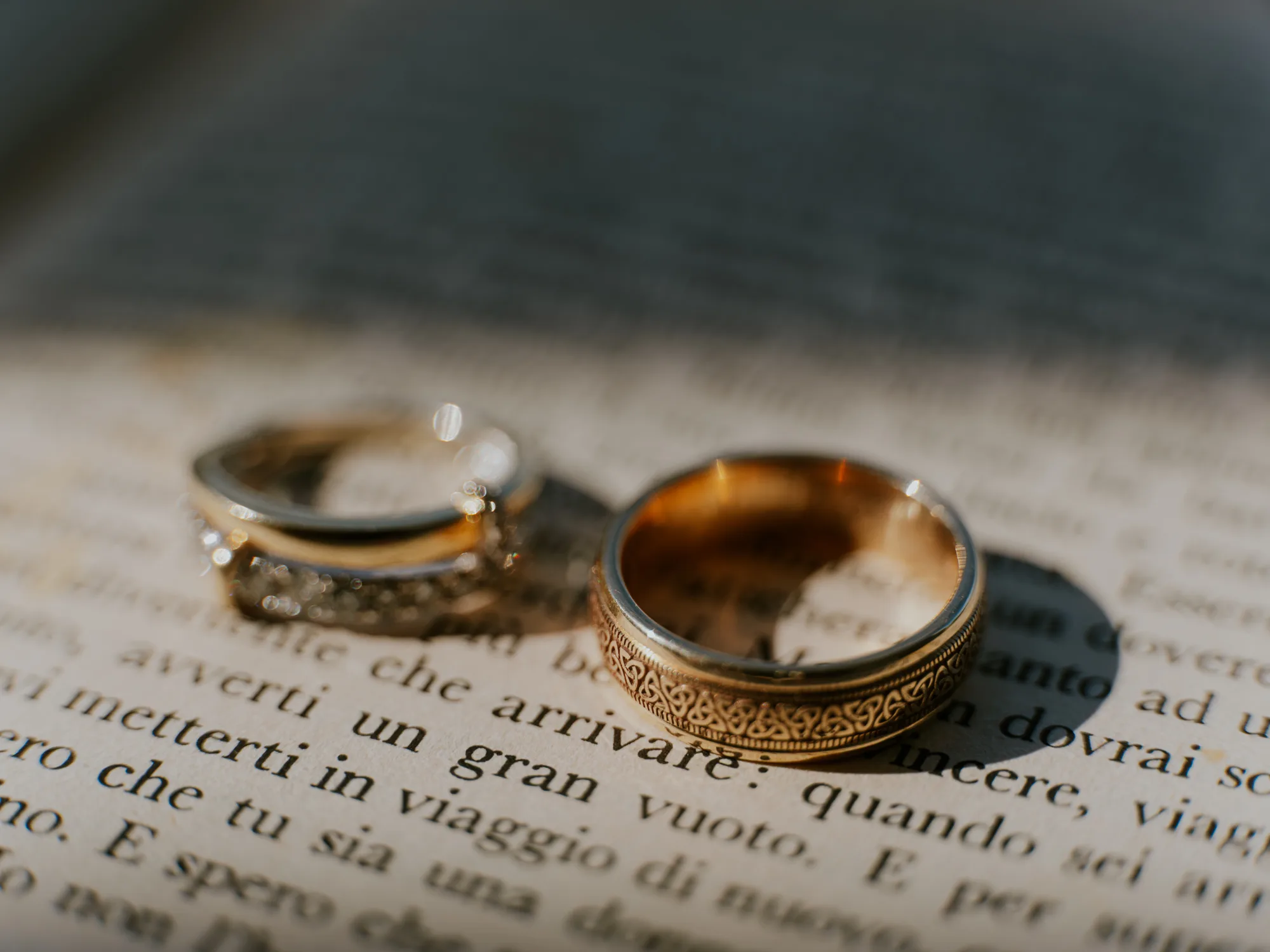 The photograph shows two wedding rings placed on an open book.