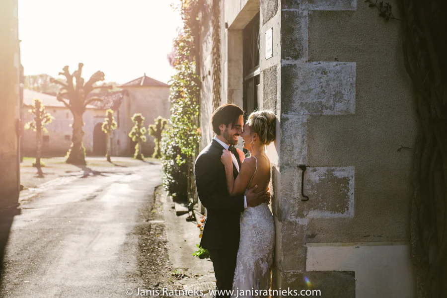 Sunlit wedding portrait against a stone village wall