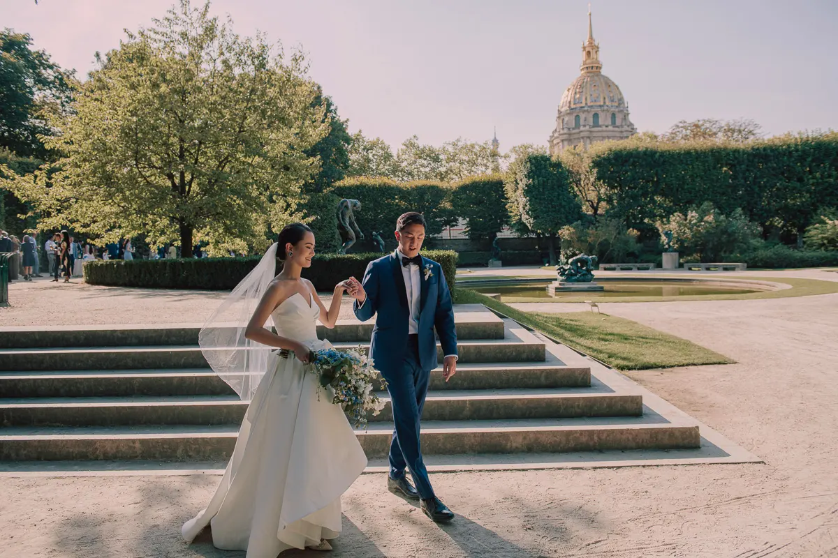 Bride and groom walking through the Musée Rodin gardens during their Paris wedding