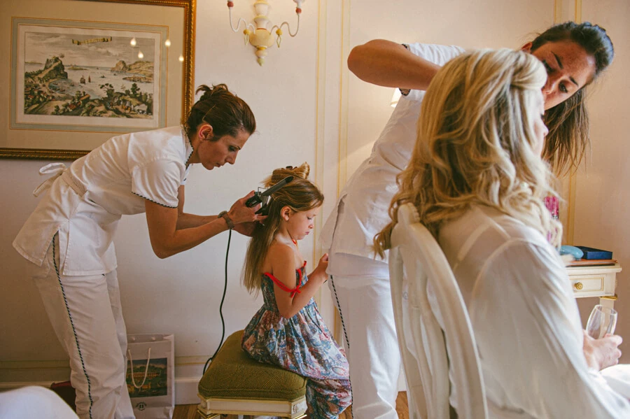 Anna having her hair prepared while the flower girls wait nearby
