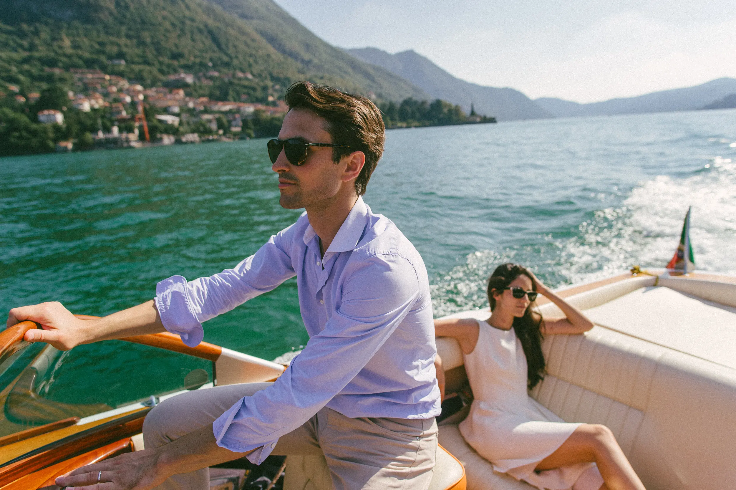 Couple on Lake Como boat with sun behind mountains