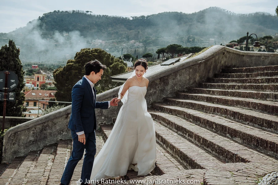 Couple in formal wedding attire walking above Santa Margherita Ligure on a misty afternoon