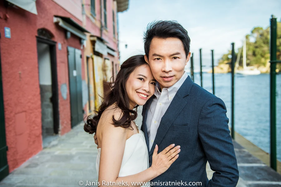Close portrait of a couple beside a red waterfront building in Portofino