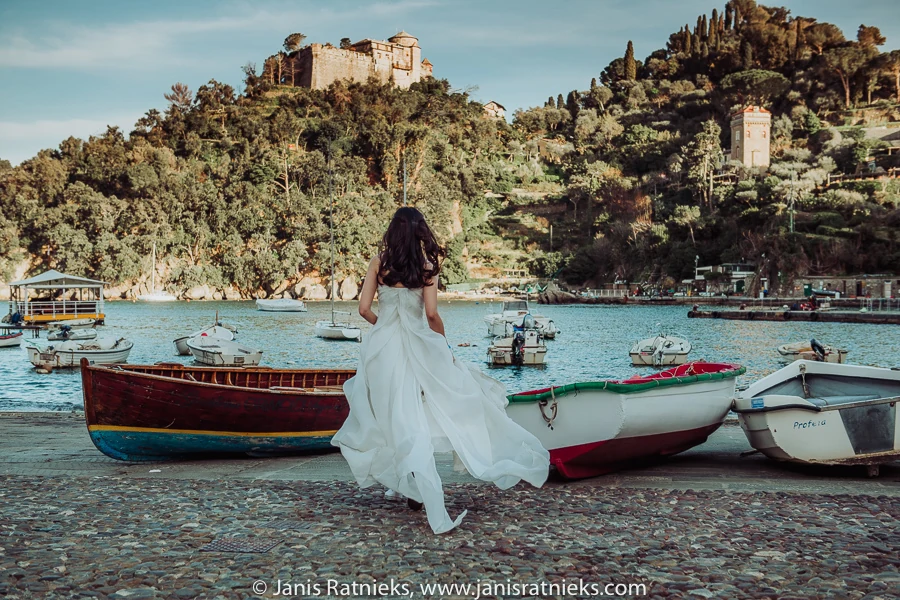 Bride in a white dress beside traditional wooden boats in Portofino harbour
