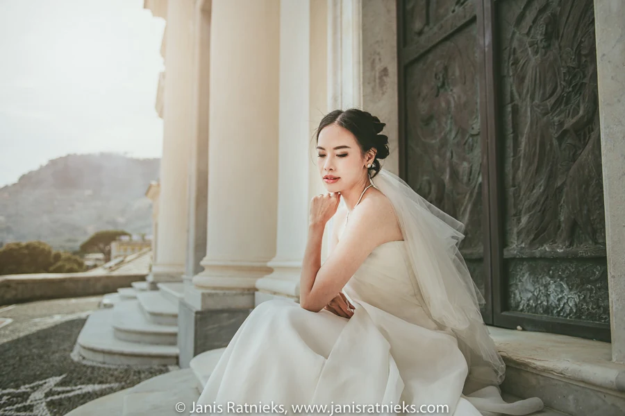 Bride in profile beside the church entrance in warm coastal light