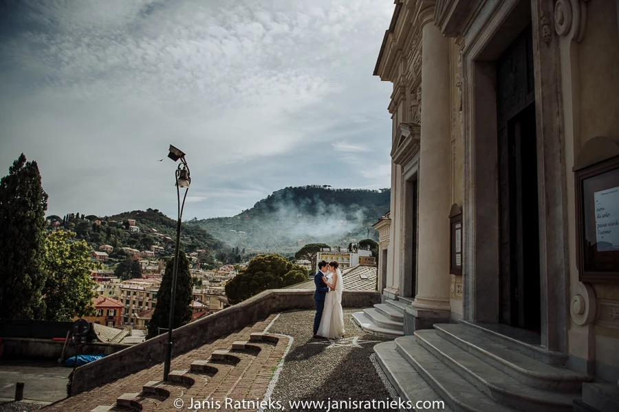 Wide couple portrait on the church steps with misty hills behind them