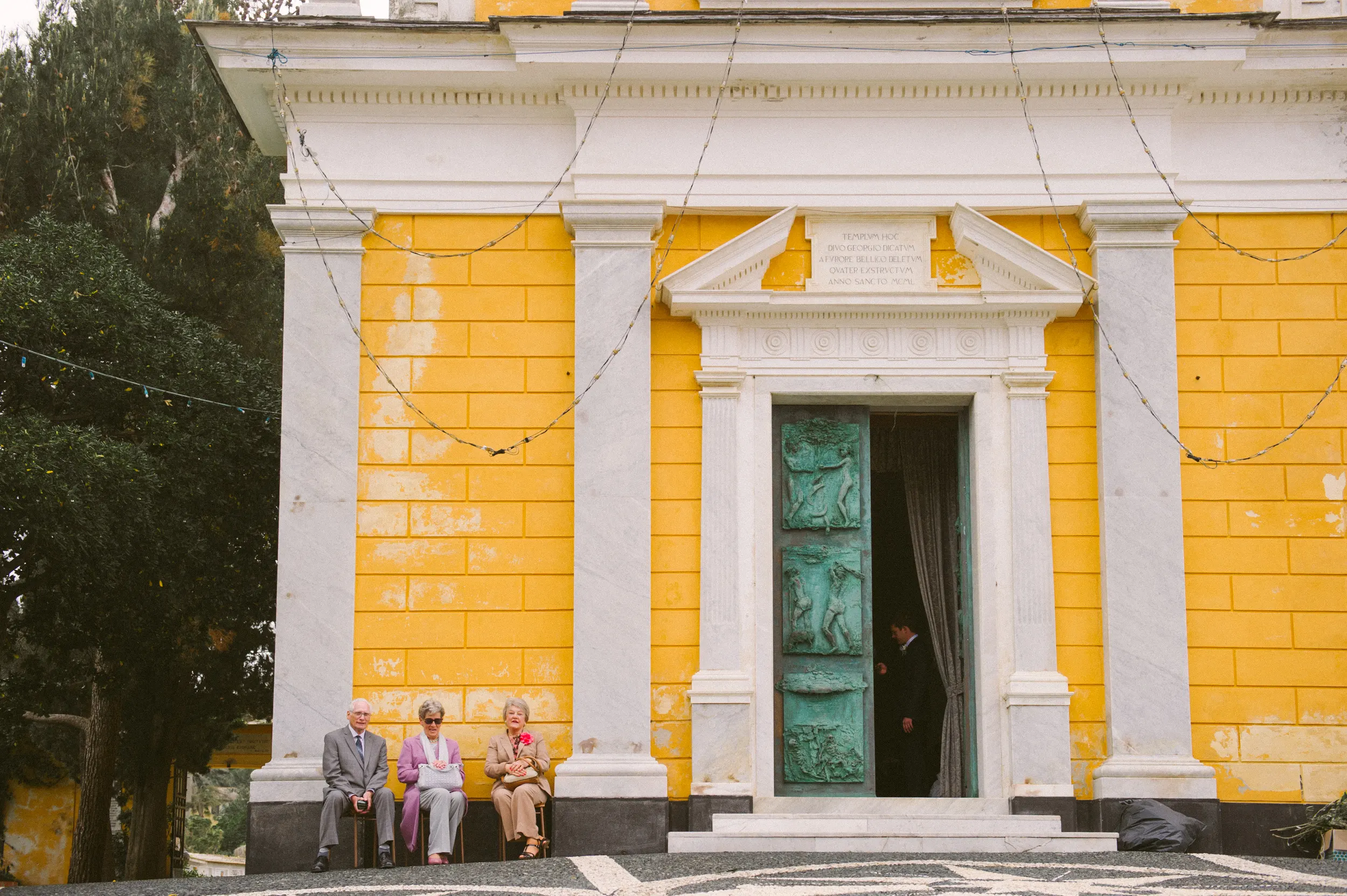 Yellow church facade in Portofino with wedding guests waiting outside