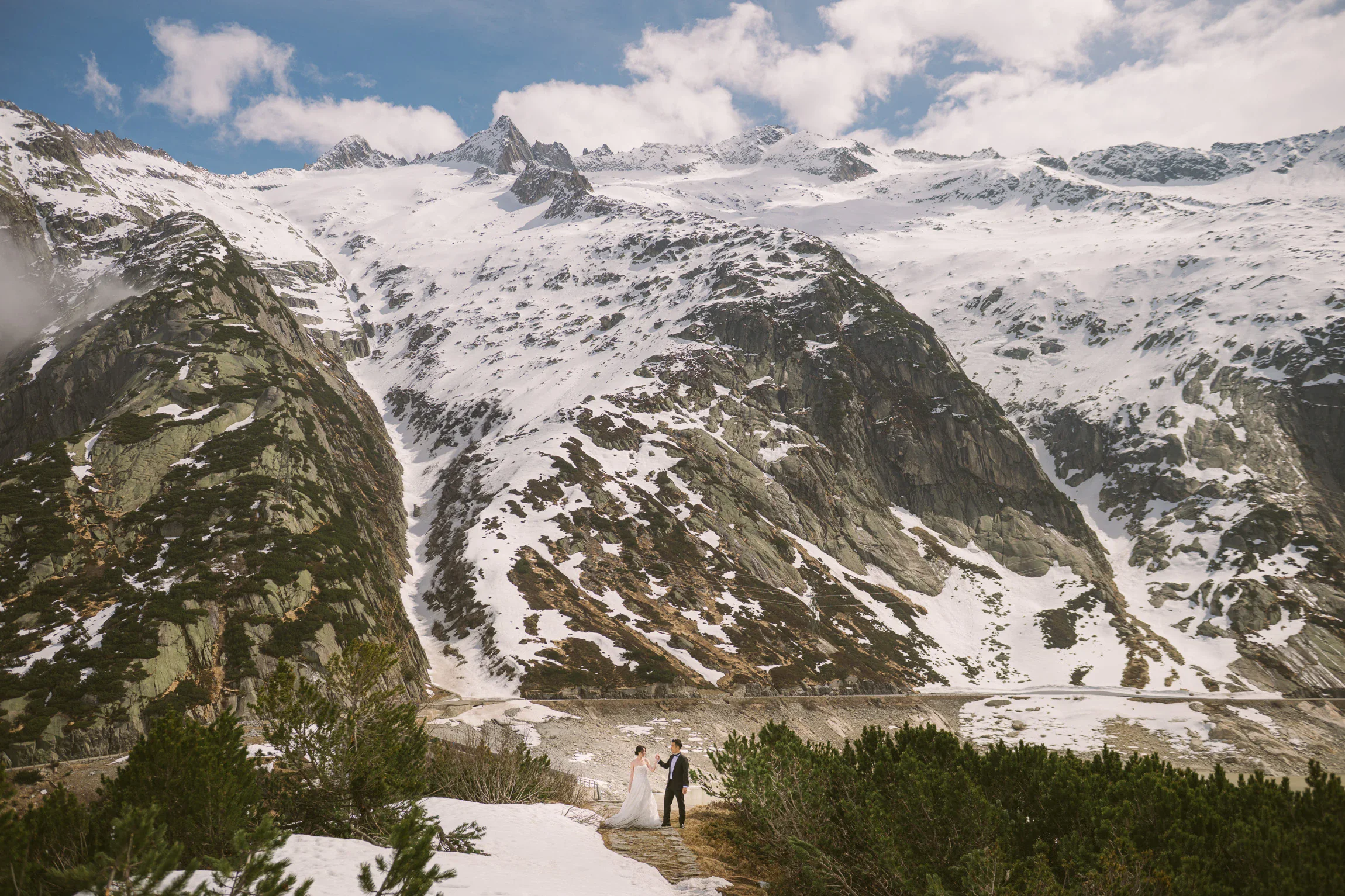 Image 8: Cinematic pre-wedding photo of Adeline and Glen standing in front of snow-covered mountains in the Swiss Alps Caption (optional)