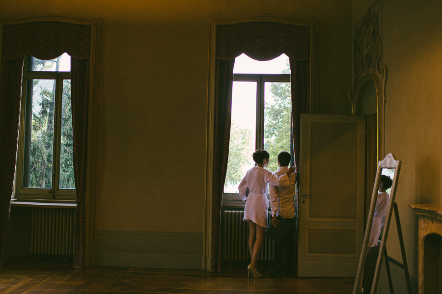 bride and groom looking from the window in villa Giuseppina