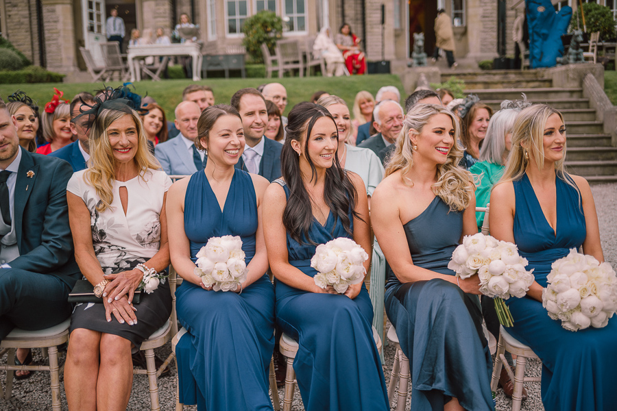 Bridesmaids in dusty blue dresses and white peony bouquets