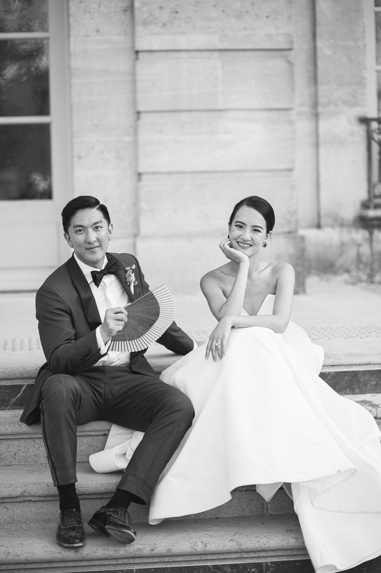 Bride and groom walking through the elegant gardens of Musée Rodin in Paris during their wedding, surrounded by sculptures and manicured greenery.