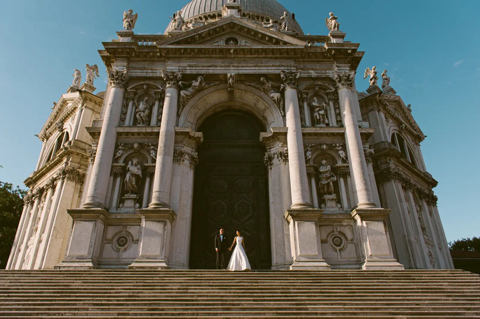 Bride and groom standing in front of the big church doors in Venice