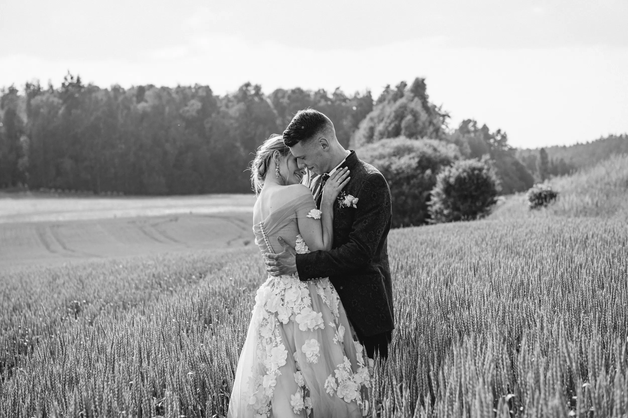 Black and white Tuscany wedding portrait of bride and groom hugging each other in a field