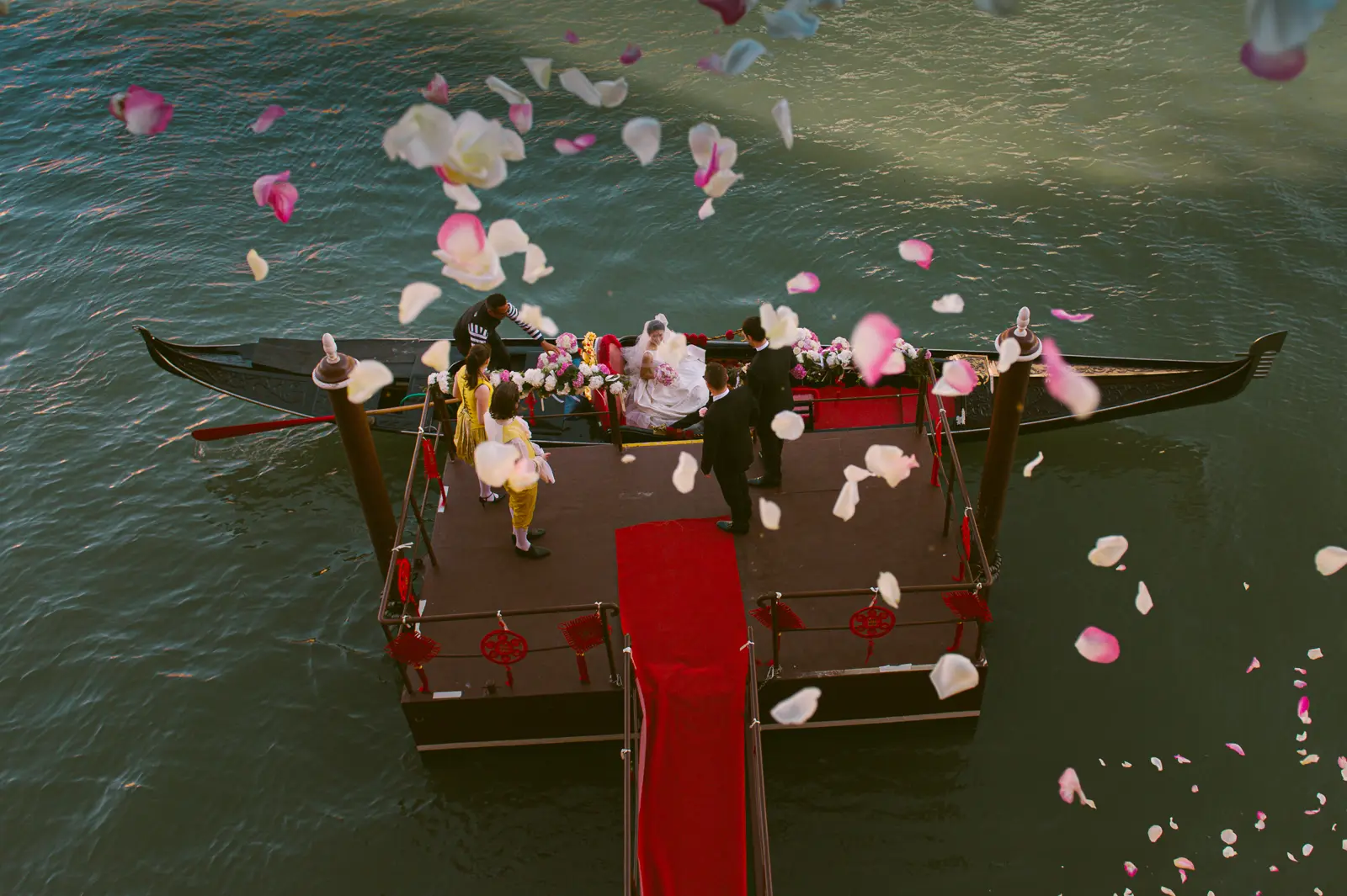 Bride arriving in wedding gondola in Venice , rose petals flying over the boat